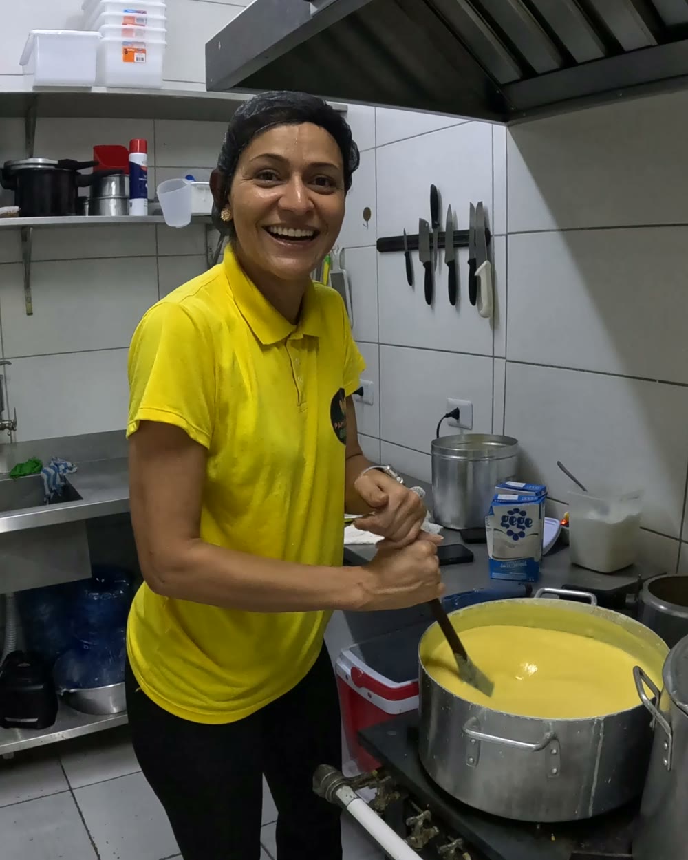 Sarah sorrindo na cozinha, mexendo a panela de pamonha